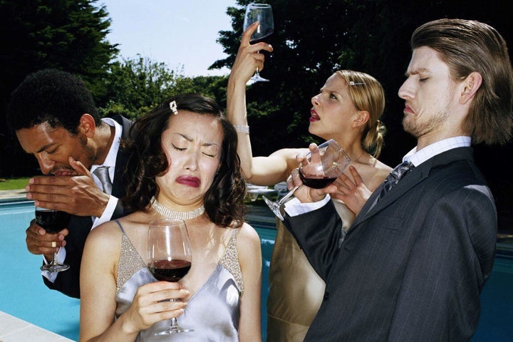 Four young people pulling faces whilst tasting red wine