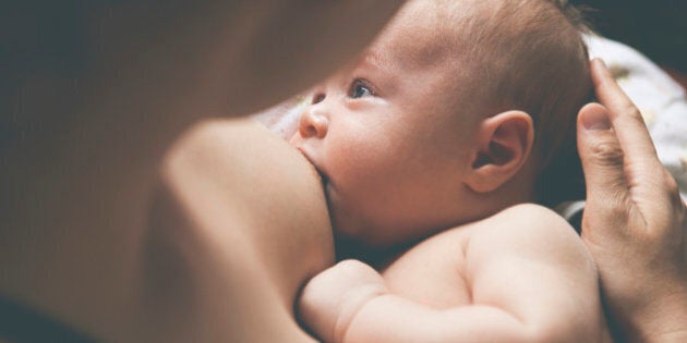 Mother holding and breast-feeding little