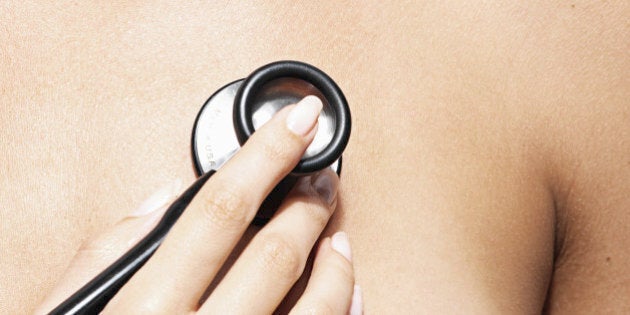 Female doctor holding stethoscope to woman's chest, close-up