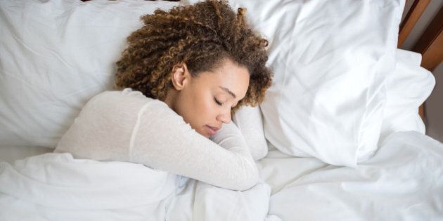 Tired African American woman sleeping in bed at home