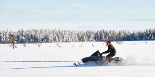 Man driving sports snowmobile in Finnish Lapland in a sunny day