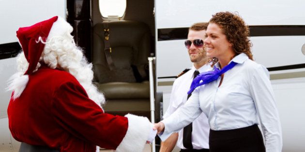 Santa Claus being greeted as he enters airplane