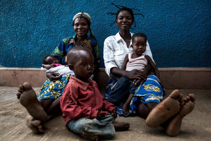 Deux mères et leurs enfants sont assises à l'extérieure d'une clinique soutenue par l'UNICEF, à Kananga.