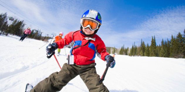 Boy smiling and skiing with family
