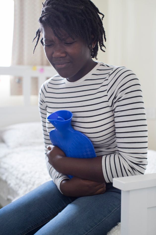 Teenage Girl In Pain Clutching Hot Water Bottle In Bedroom