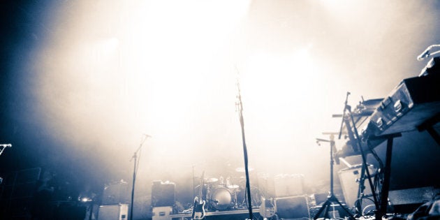 Empty illuminated stage with drumkit, guitar and microphones