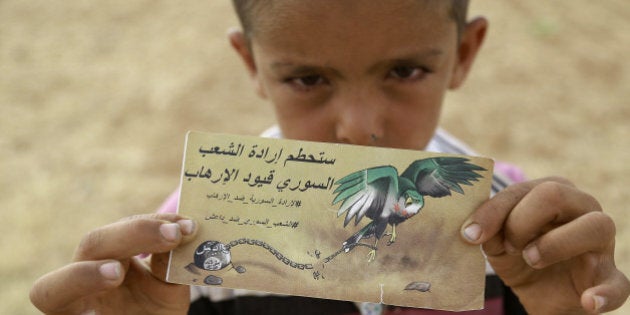 A young Syrian boy holds a banner dropped by a Syrian Democratic Forces (SDF) alliance plane reading in Arabic: 'The will of the Syrian people will break the chains of the terrorists' as US-backed Kurdish and Arab fighters advance into the Islamic State (IS) jihadist's group bastion of Manbij, in northern Syria, on June 23, 2016.Backed by air strikes by the US-led coalition bombing IS in Syria and Iraq, fighters with the Syrian Democratic Forces (SDF) alliance entered Manbij from the south, a monitoring group said. / AFP / DELIL SOULEIMAN (Photo credit should read DELIL SOULEIMAN/AFP/Getty Images)