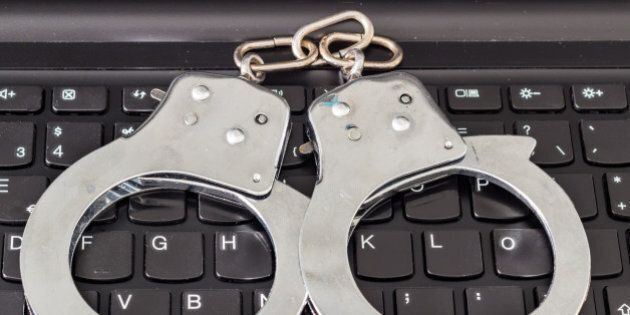 Handcuffs on keyboard, symbolizing computer decurity and police investigation