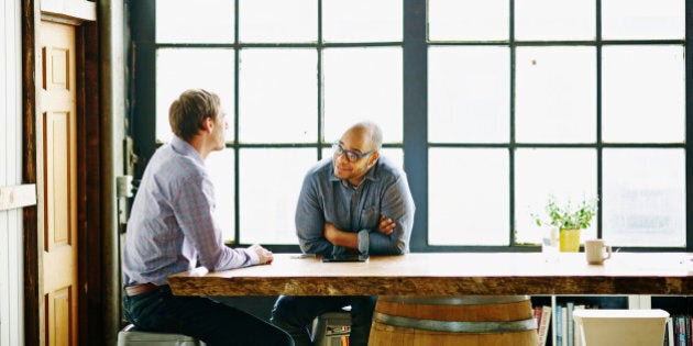 Smiling businessman in discussion with colleague at conference table in startup office