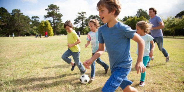 Children, aged 9-10, running together with a soccer ball in a park