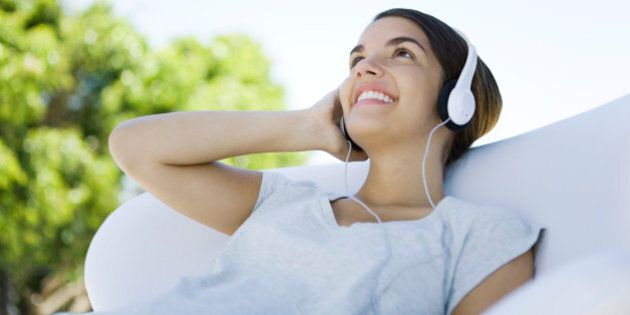 Teenage girl listening to headphones, looking up, smiling