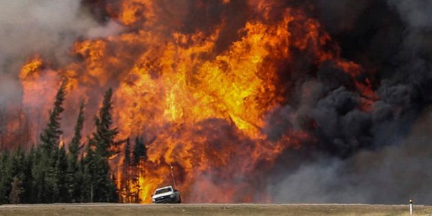 Smoke and flames from the wildfires erupt behind a car on the highway near Fort McMurray, Alberta, Canada, May 7, 2016. REUTERS/Mark Blinch/File Photo