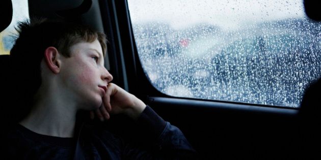 Young boy looking out rainy car window