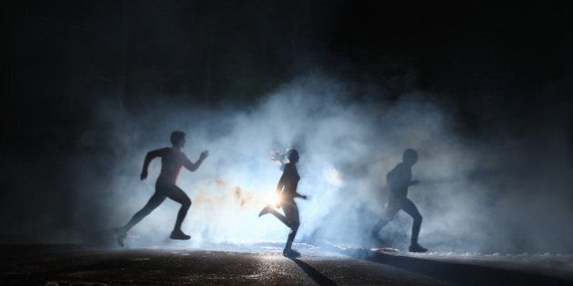 Three runners on foggy road at night