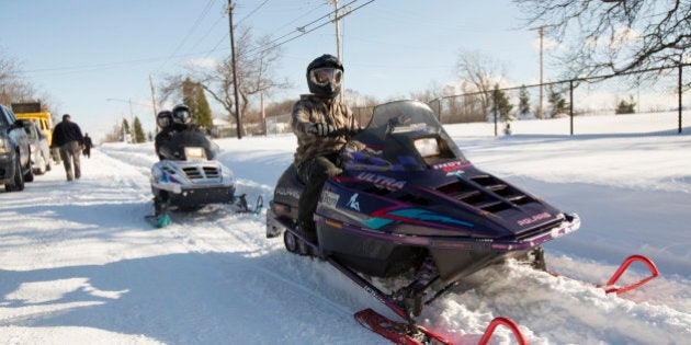 People ride snowmobiles through the streets in Buffalo, New York, November 21, 2014. Warm temperatures and rain were forecast for the weekend in the city of Buffalo and western New York, bringing the threat of widespread flooding to the region bound for days by deep snow. Areas where several feet of snow fell this week should brace for significant, widespread flooding, the National Weather Service warned on Friday. REUTERS/Lindsay DeDario (UNITED STATES - Tags: ENVIRONMENT)