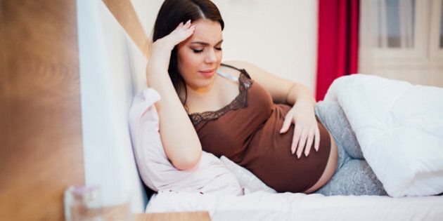 Beautiful pregnant woman struggling with headache and resting