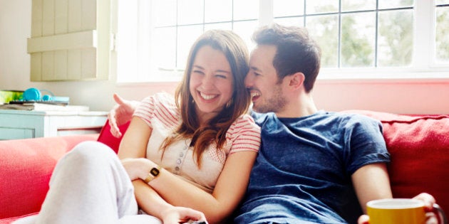 Young couple laugh together as they relax on sofa