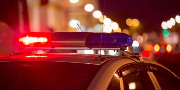 Red light flasher atop of a police car. City lights on the background.