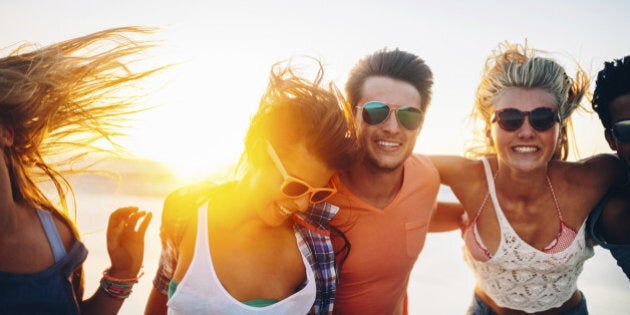 Friends dancing on beach in sunset