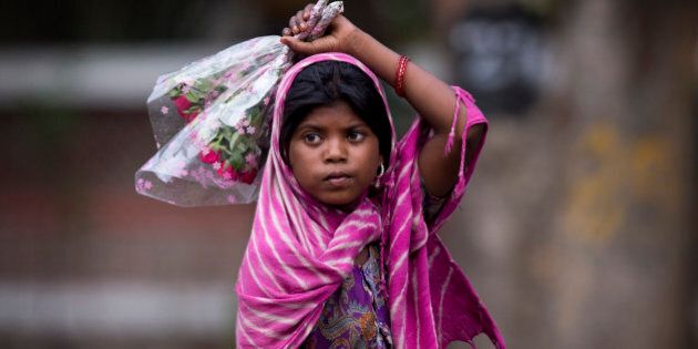 A young girl waits for cars to stop at the traffic light to sell flowers to commuters at a busy cross road in New Delhi, India, Wednesday, June 1, 2016. As they garner better sales due to sympathetic reasons, children are often forced by families to beg or sell small items for hours irrespective of weather conditions. (AP Photo/Saurabh Das)