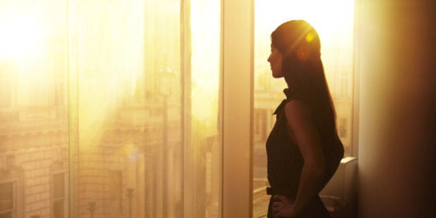 Business woman looking over the city at sunrise.