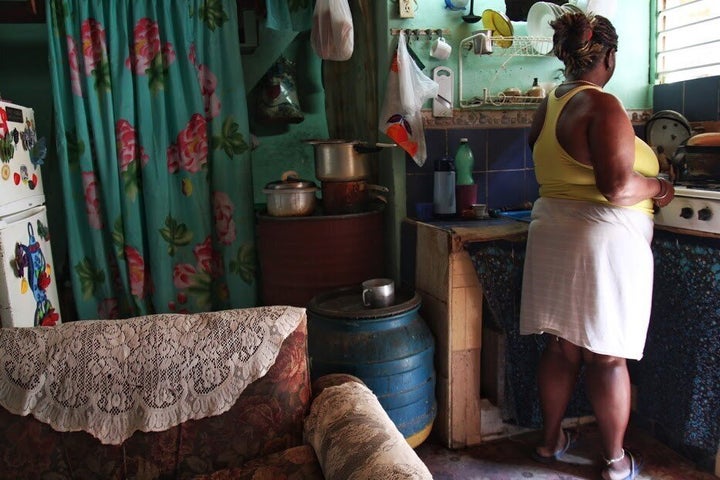 Olivia-mère dans son grand douze pieds par douze pieds, mais avec un deuxième étage de même dimension. Elle termine le lavage de sa vaisselle.