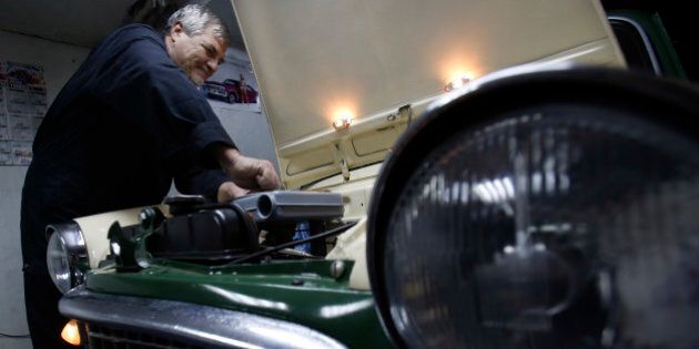 In this file dated Friday, Nov. 28, 2014, Bosnian man Oto Novak works on a Fiat 1100 at his garage, in Bosnian town of Tuzla, 100 kms north of Sarajevo. Novak, 63, spends his retirement days restoring his 1959 Fiat 1100 with spare parts he buys on the internet. Despite their high price for his 300 euro Bosnian pension, Novak still pursues his life-long passion, fixing up this old timer car which has taken three years so far.