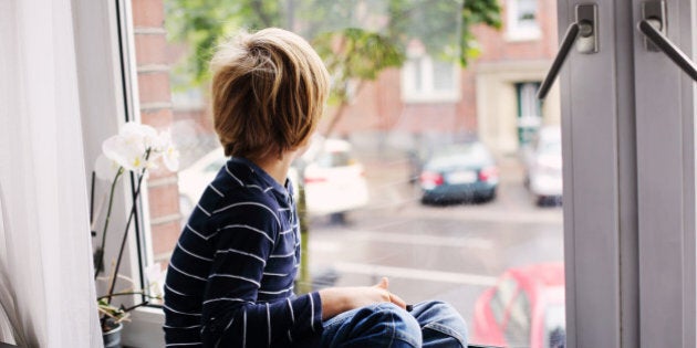 7 year old boy sitting near the window and playing tablet