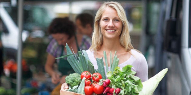 Portrait of mid adult women holding box of vegetables from market