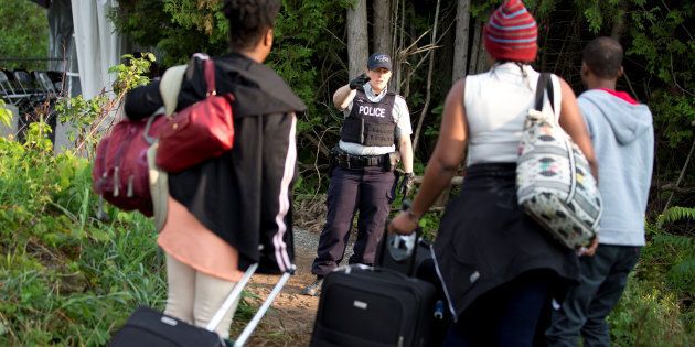 Une agente de la Gendarmerie royale du Canada accueille une famille d'origine haïtienne qui tente d'entrer au Canada par le chemin Roxham, à la frontière avec les États-Unis, en 2017.