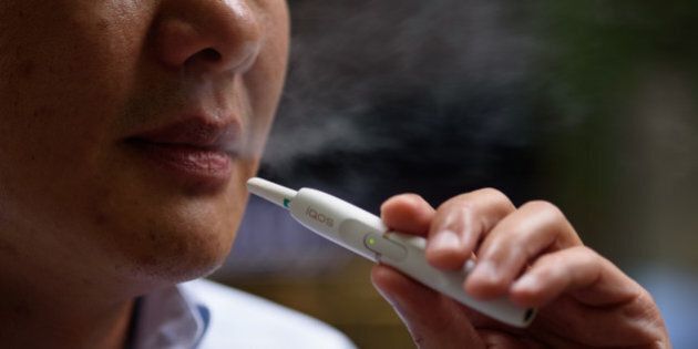 A man smokes a Philip Morris International Inc. iQOS electronic cigarette in this arranged photograph in Tokyo, Japan, on Tuesday, Aug. 23, 2016. Philip Morris International and Japan Tobacco Inc. have rolled out products that are heated -- not burned -- in battery-charged devices, seeking to appeal to smokers who want their nicotine fix without the usual smell and smoke. Photographer: Akio Kon/Bloomberg via Getty Images