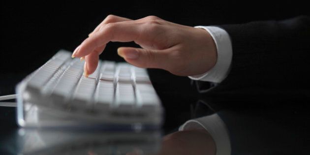 Woman typing on computer keyboard, close-up of hand