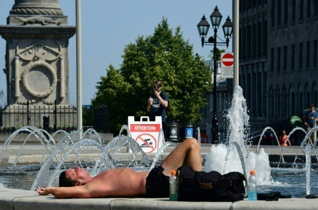 Un homme profite du soleil sur le bord d'une fontaine à Montréal.