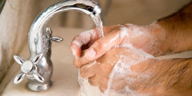Man washing his hands under running water in washbasin