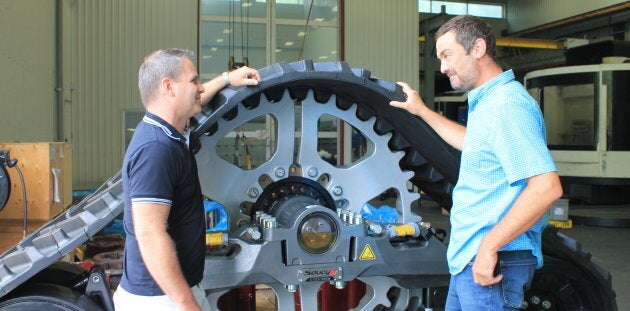 Les deux hommes en compagnie d'une chenille pour tracteurs produite dans leur usine.