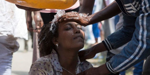TOPSHOT - Men wash the face of a woman after police used teargas during the Oromo new year holiday Irreechaa in Bishoftu on October 2, 2016.Several people were killed in a stampede near the Ethiopian capital on October 2, according to an AFP photographer at the scene. Several thousand people from the Oromo community gathered at a sacred lake for a religious festival and started to cross their wrists above their heads, a symbol of Oromo anti-government protests. The event quickly degenerated, with protesters throwing stones and bottles and security forces responding with baton charges and tear gas grenades. Together, Oromos and Amharas make up 60 percent of the population and have become increasingly vocal in rejecting what they see as the disproportionate power wielded by the northern Tigrean minority in government and the security forces. / AFP / Zacharias ABUBEKER (Photo credit should read ZACHARIAS ABUBEKER/AFP/Getty Images)