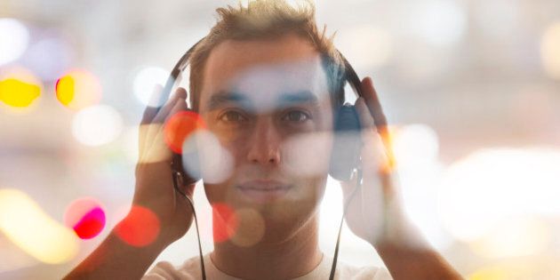 man listening to headphones and abstract city light double exposure