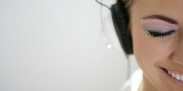Cropped view of young happy woman listening to headphones