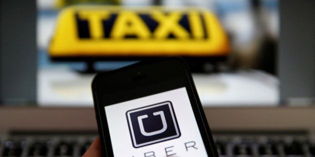 An illustration picture shows the logo of car-sharing service app Uber on a smartphone next to the picture of an official German taxi sign September 15, 2014. REUTERS/Kai Pfaffenbach/Illustration/File Photo