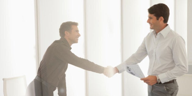 Two businessmen in boardroom shaking hands