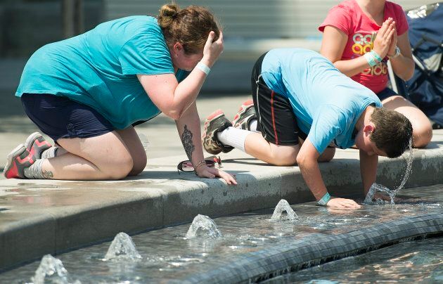 Des Montréalais se rafraîchissent à une fontaine pendant la canicule, le 2 juillet 2018.