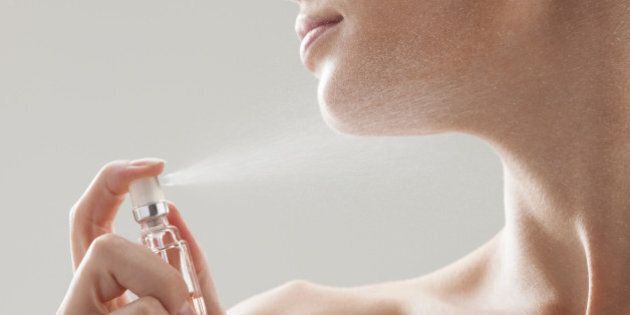 Beautiful woman spraying perfume on her neck
