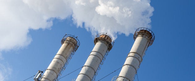 Smoking pipes making clouds against blue sky background. Dioxide air contamination. Environmental pollution.