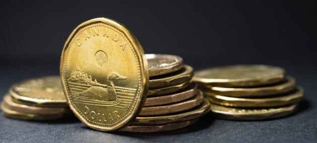 A Canadian dollar coin standing in front of coins