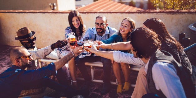 Multi-ethnic friends celebrating and toasting with wine and beer at rustic country house in Italy