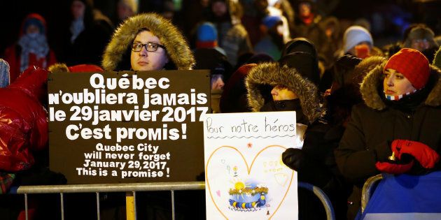 Les gens tiennent des pancartes de soutien lors d'une vigile soulignant la première Commémoration des victimes de la fusillade mortelle survenue au Centre Culturel Islamique de Québec à Québec, en janvier 2018.