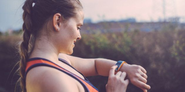 Woman using smart watch outdoor before having a running workout.