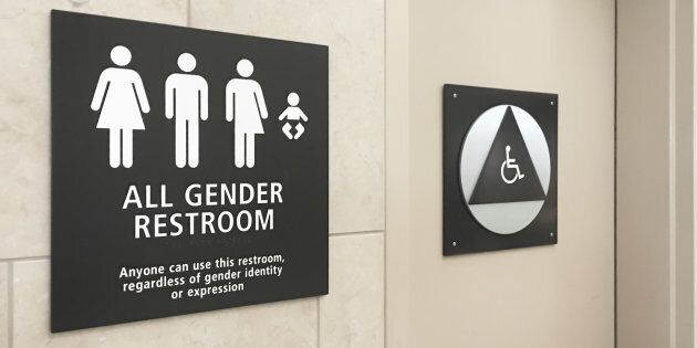 Des toilettes neutres dans un aéroport, avec l'inscription suivante: «Tout le monde peut utiliser ces toilettes, sans égard à l'identité ou l'expression de leur genre.»