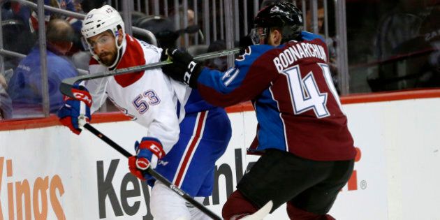 Montreal Canadiens left wing Lucas Lessio, left, is checked into the boards while passing the puck by Colorado Avalanche defenseman Andrew Bodnarchuk in the second period of an NHL hockey game Wednesday, Feb. 17, 2016, in Denver. (AP Photo/David Zalubowski)