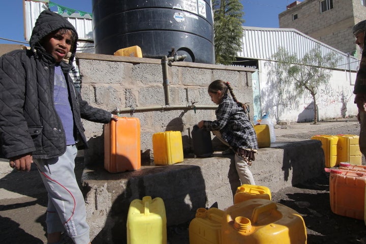 Le mercredi 13 décembre 2017 : Des enfants remplissent des jerricans d'eau potable à un réservoir d'eau situé dans une rue de Sanaa, dans le gouvernorat de Sanaa, au Yémen.